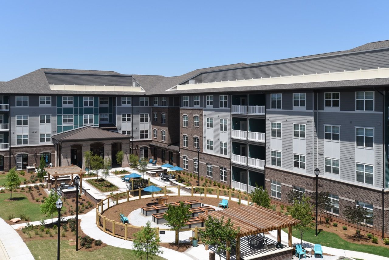 Exterior courtyard of a modern apartment community with seating and umbrellas.