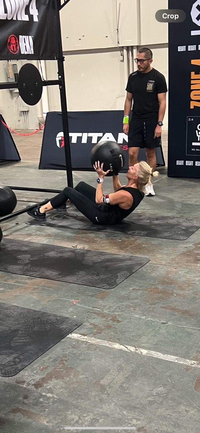 A woman is doing sit ups with a medicine ball in a gym.