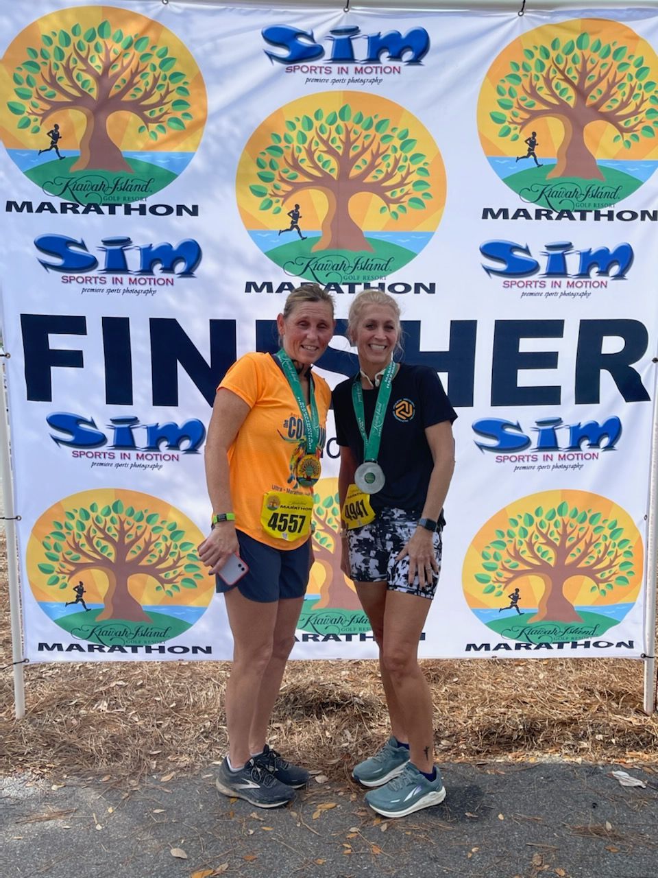 Two women standing in front of a banner that says finisher sim