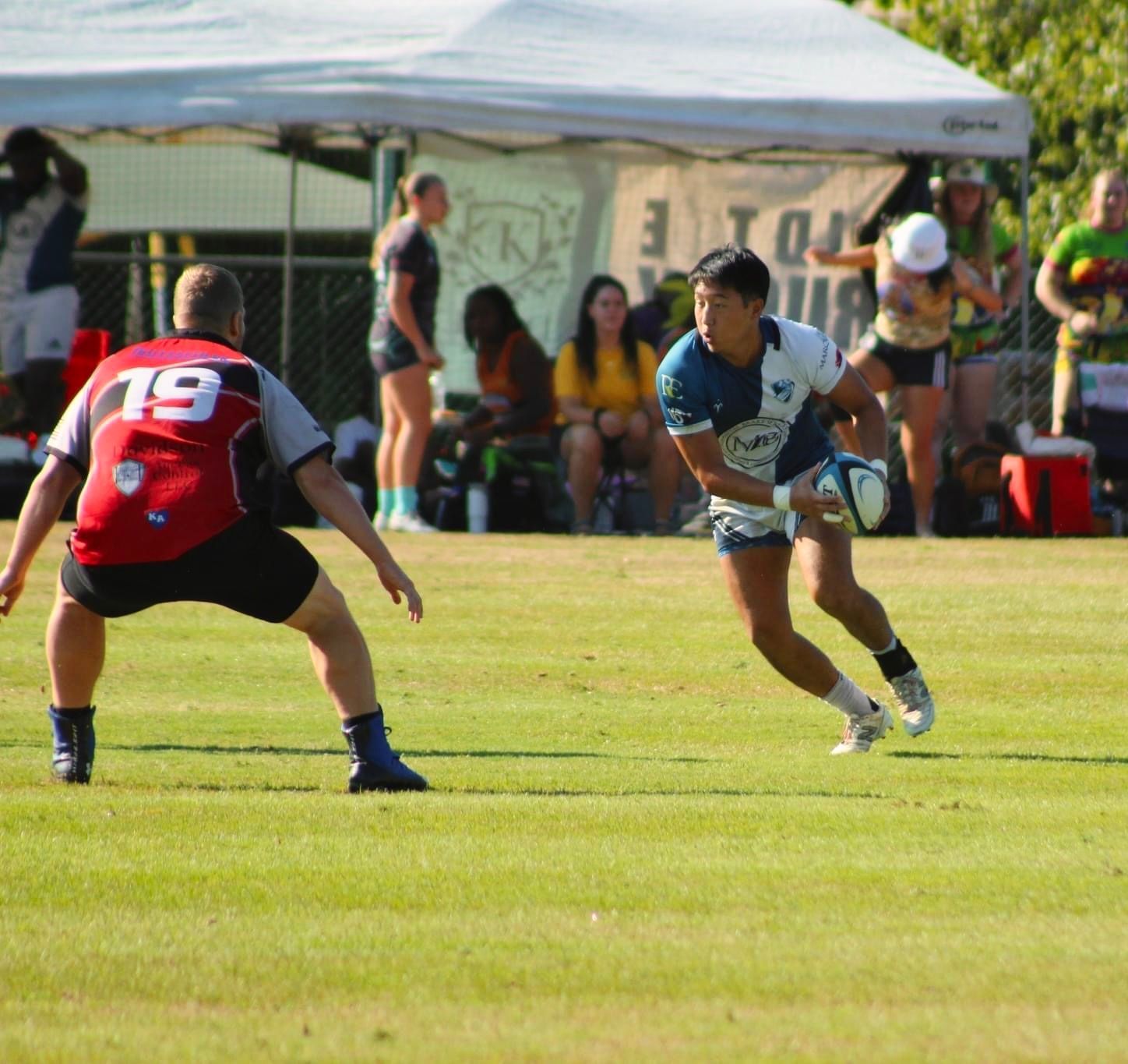 A man with the number 19 on his back is running with a rugby ball