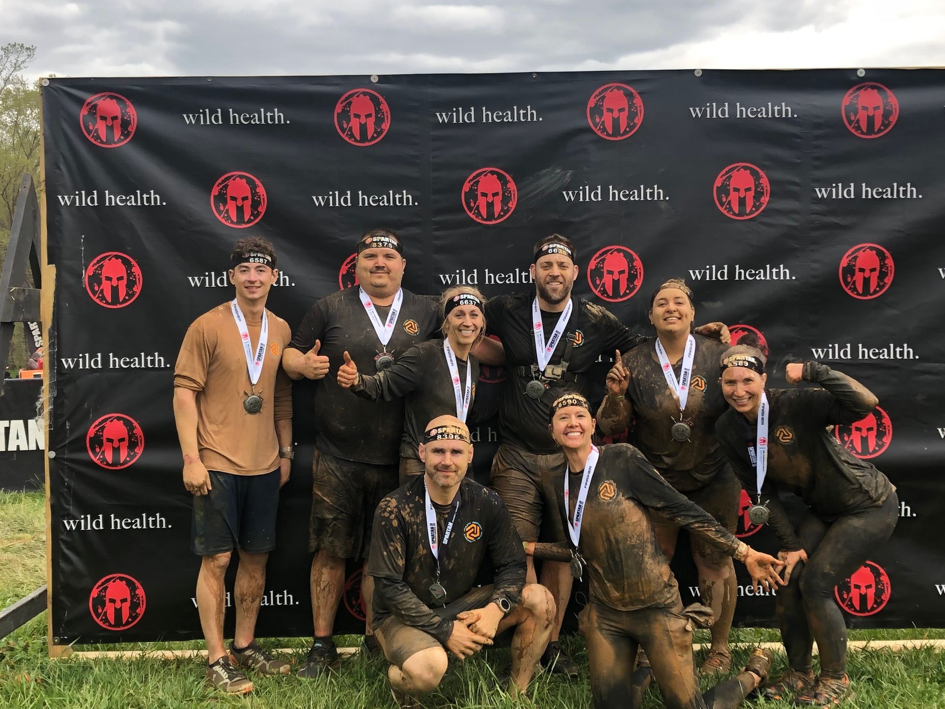 A group of people are posing for a picture in front of a spartan wall.