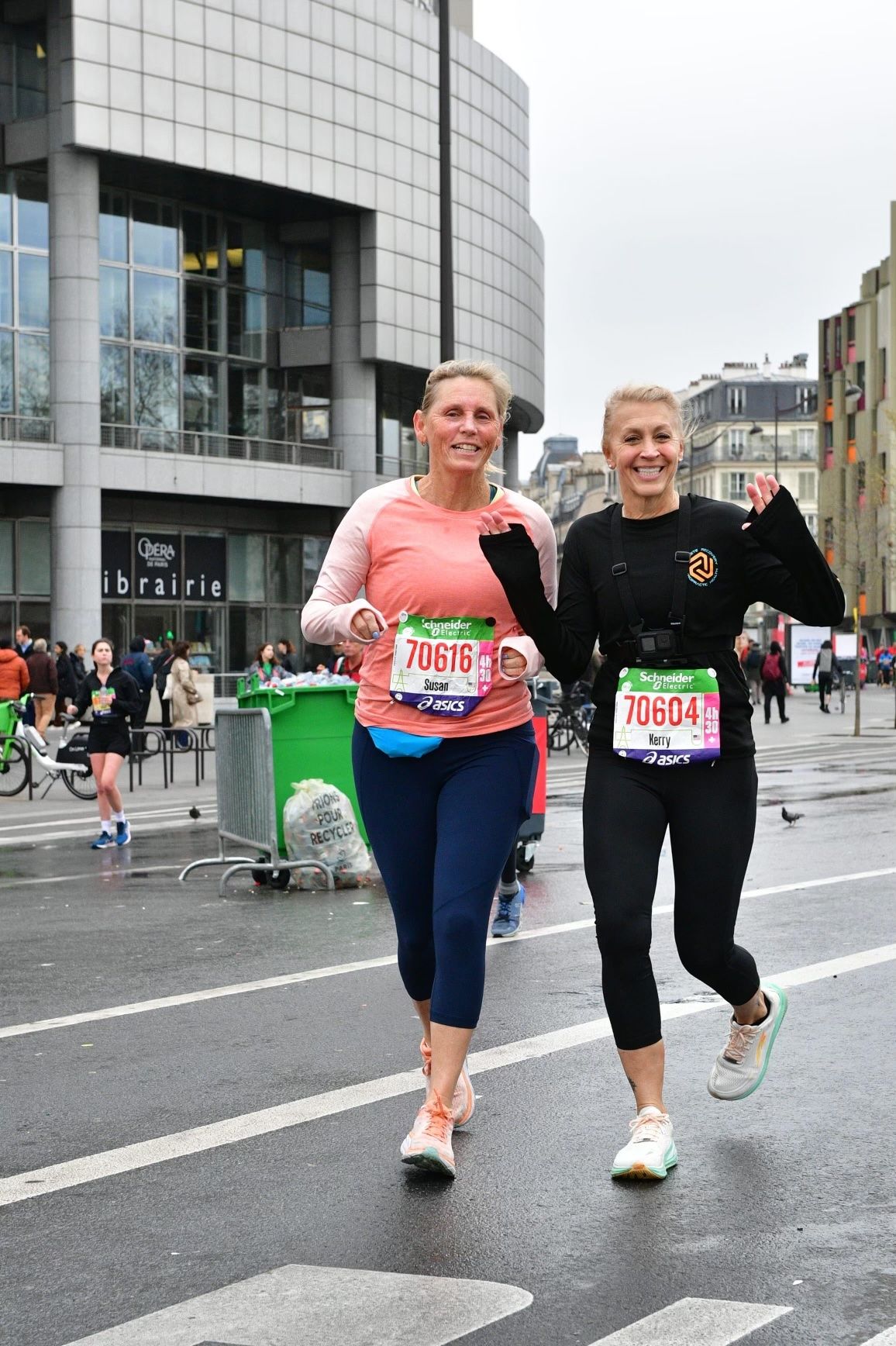 Two women are running a marathon on a city street.