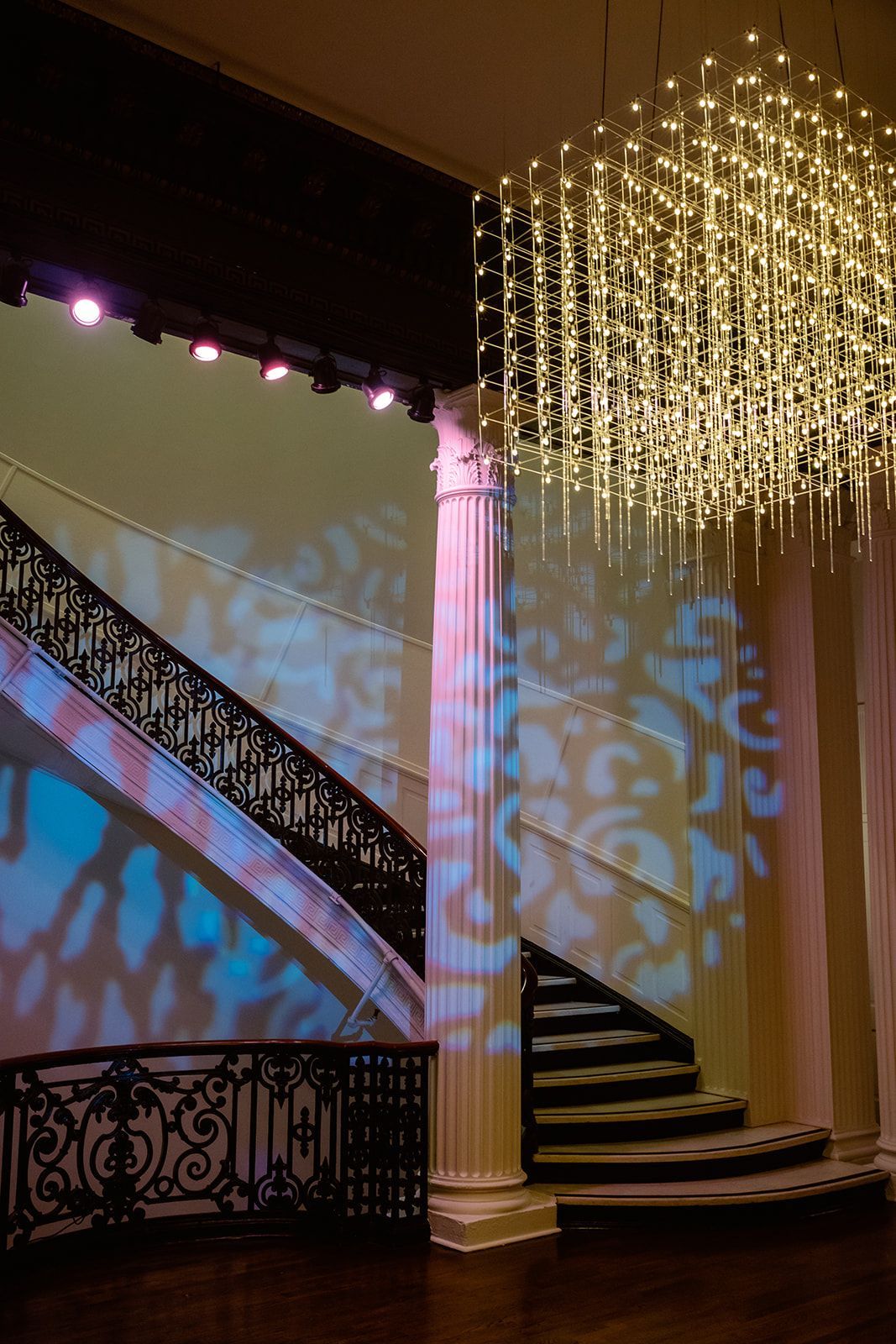 A staircase with a chandelier hanging from the ceiling in a room.
