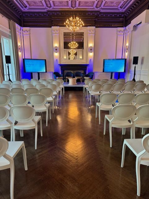 Rows of white chairs are lined up in a large room.