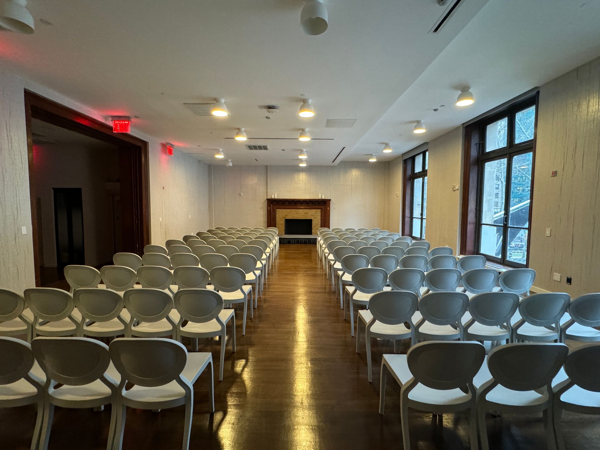 Rows of chairs are lined up in a large room with a fireplace.