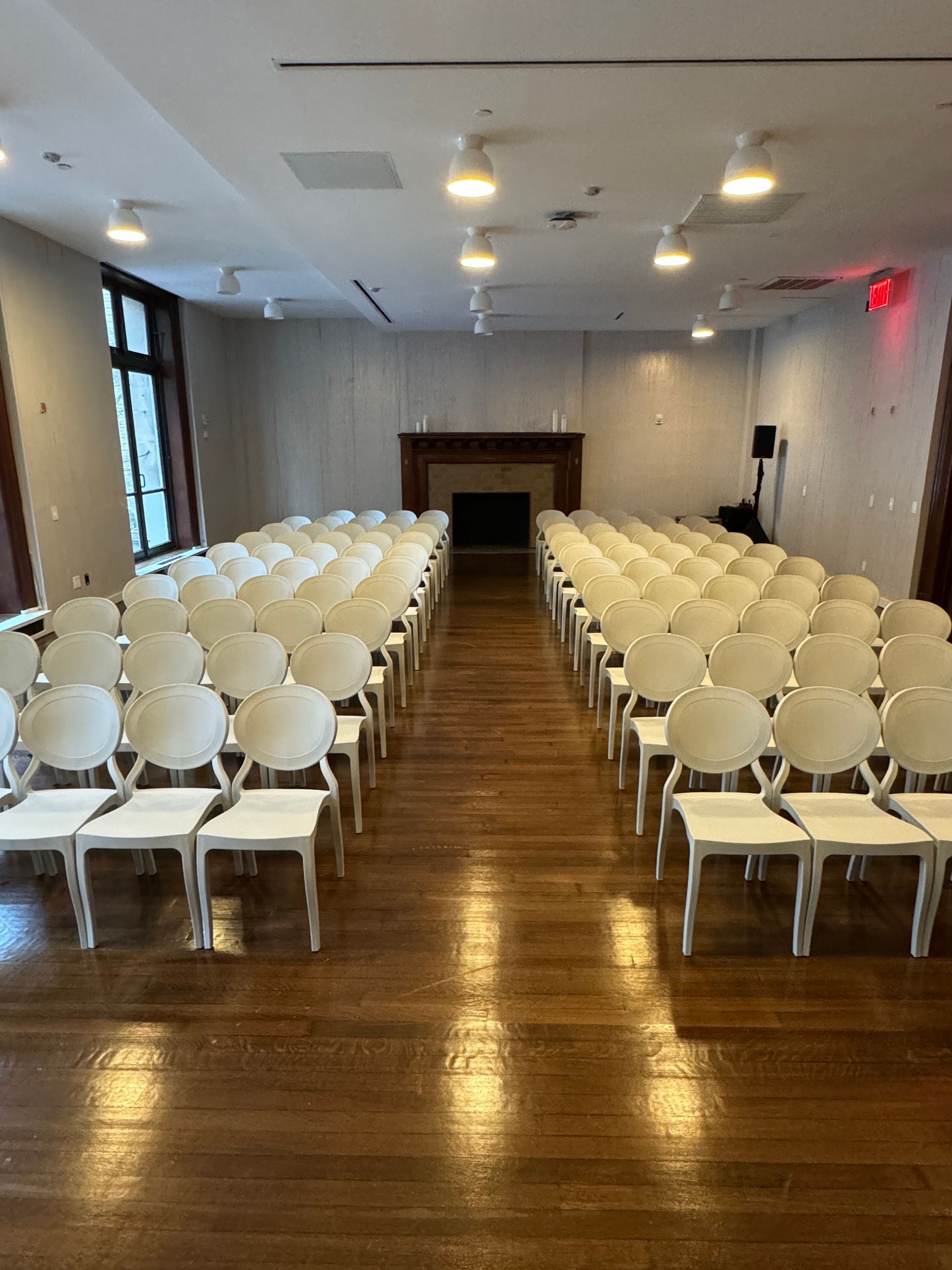 Rows of white chairs are lined up in a large room.