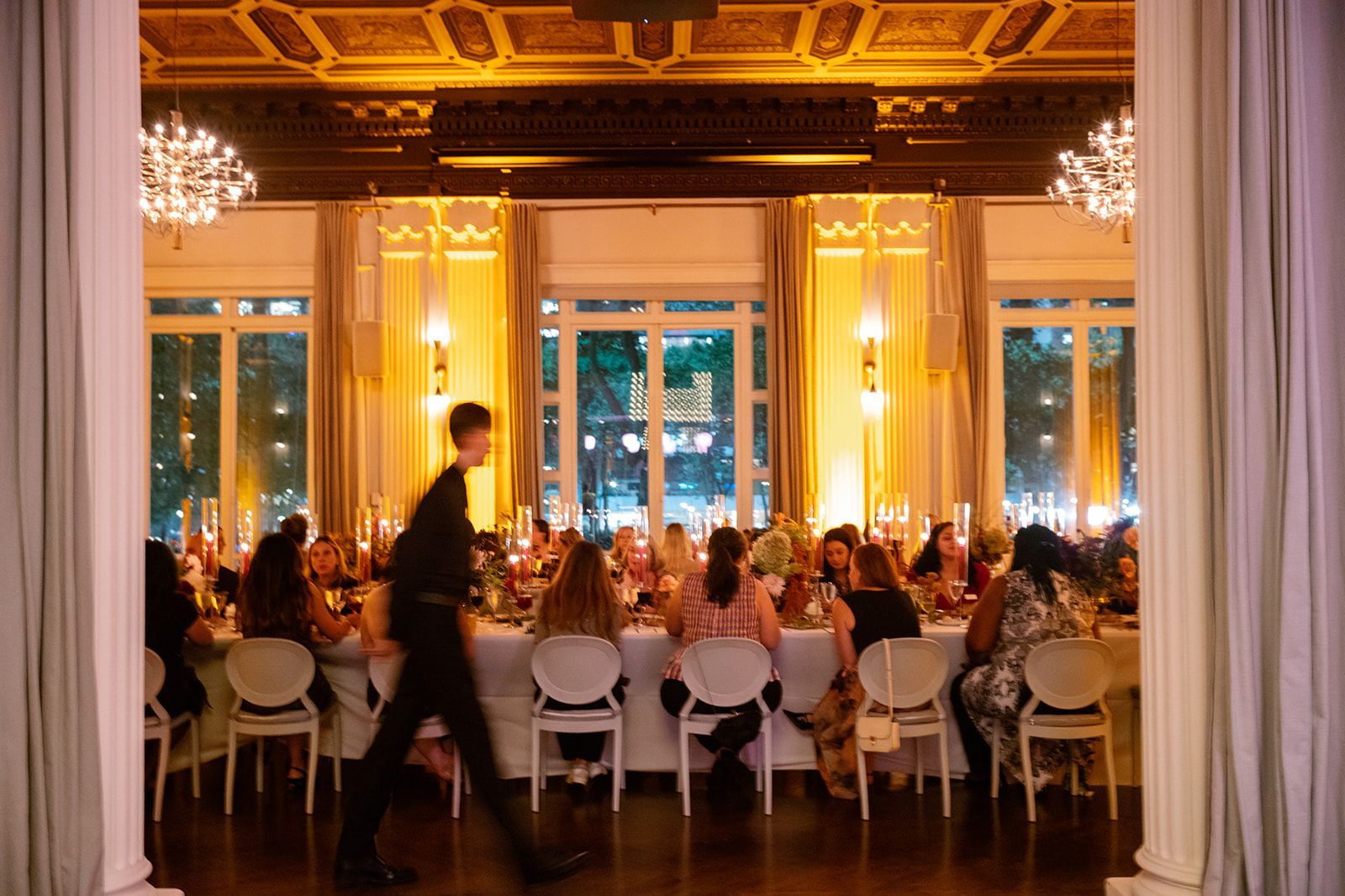 A group of people are sitting at tables in a large room at a wedding reception.