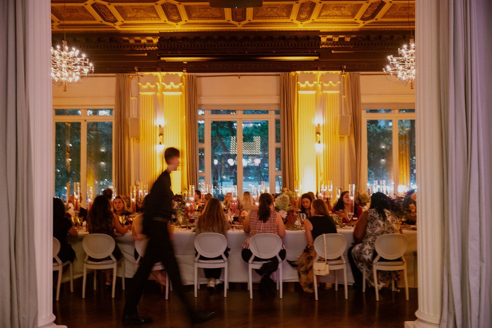 A group of people are sitting at tables in a large room at a wedding reception.