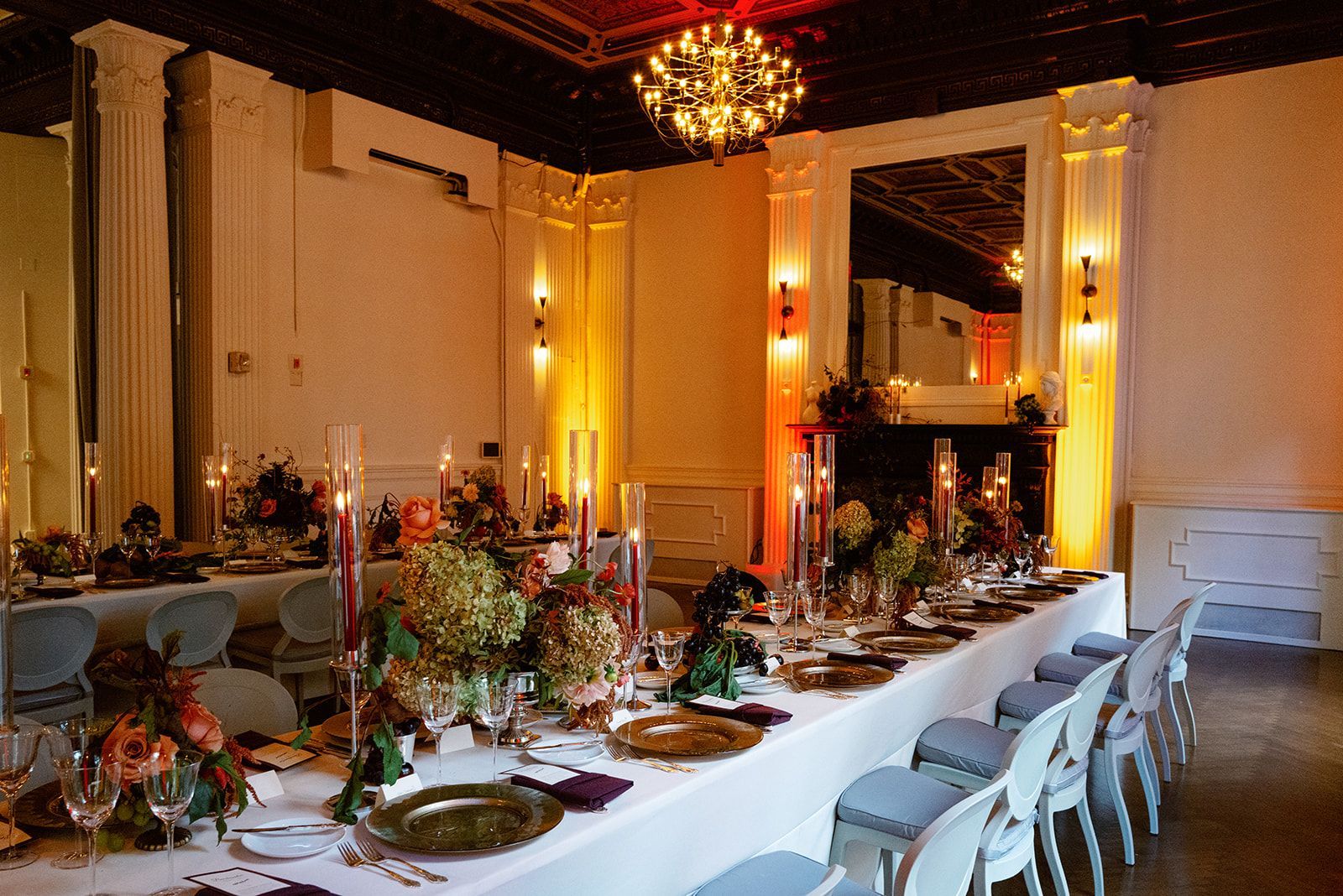 A long table with plates , candles and flowers in a room.