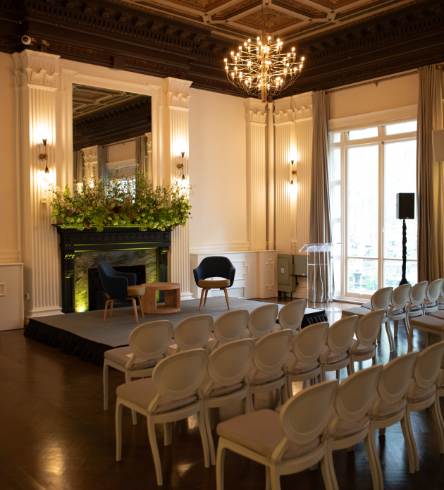 A room with rows of chairs and a fireplace