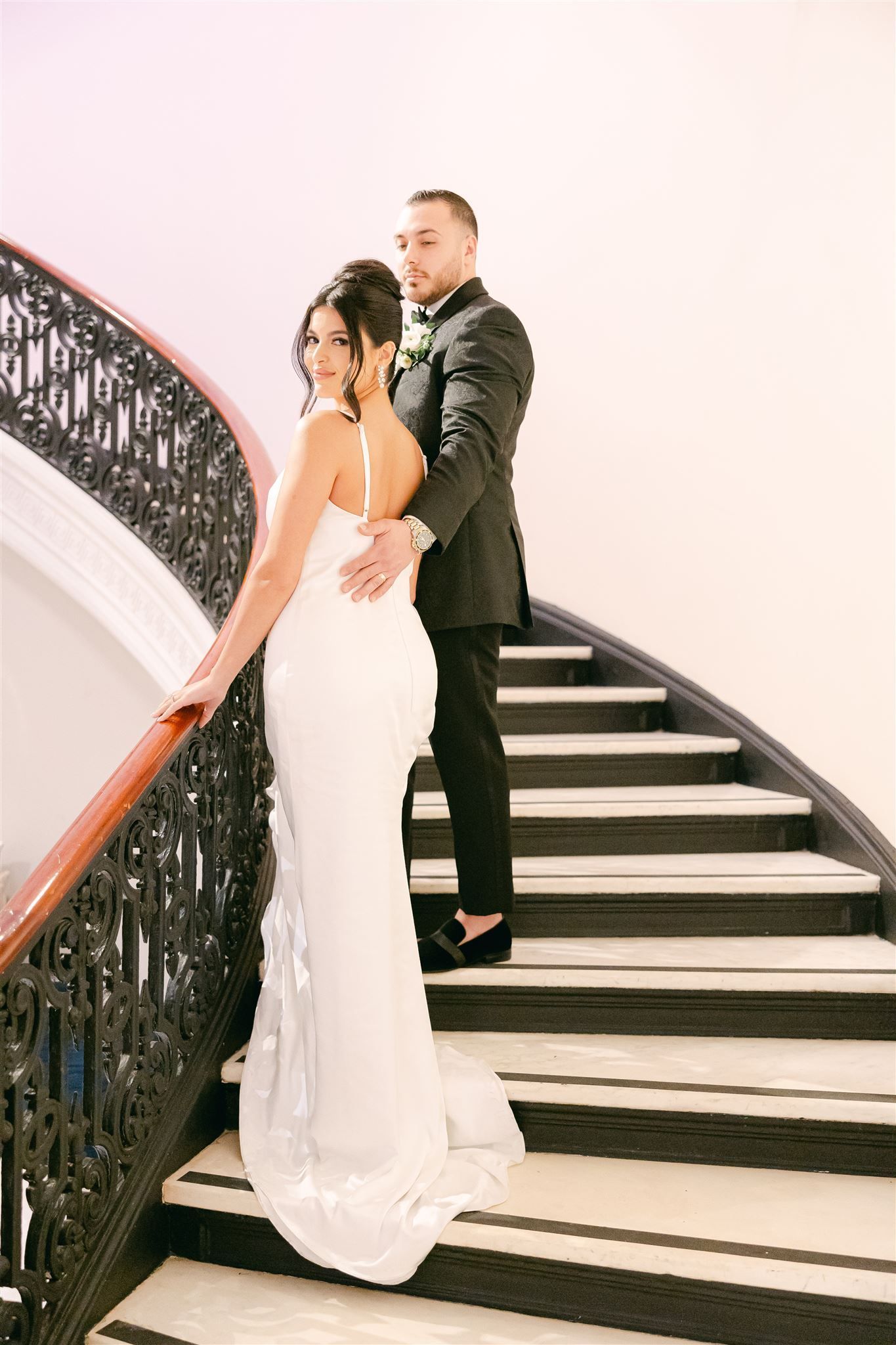 a bride and groom are standing on a set of stairs .