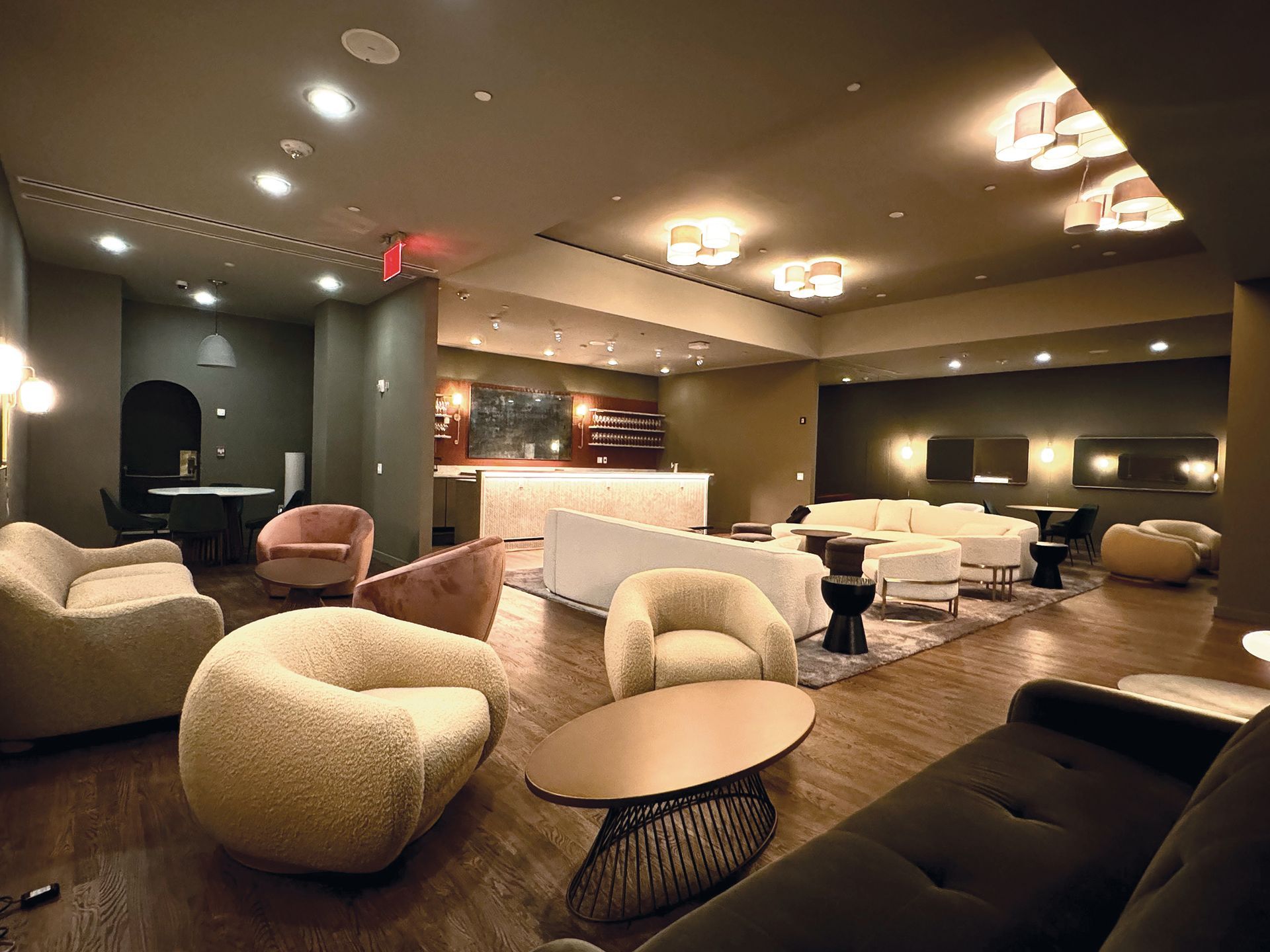 A living room with a lot of furniture and a red exit sign