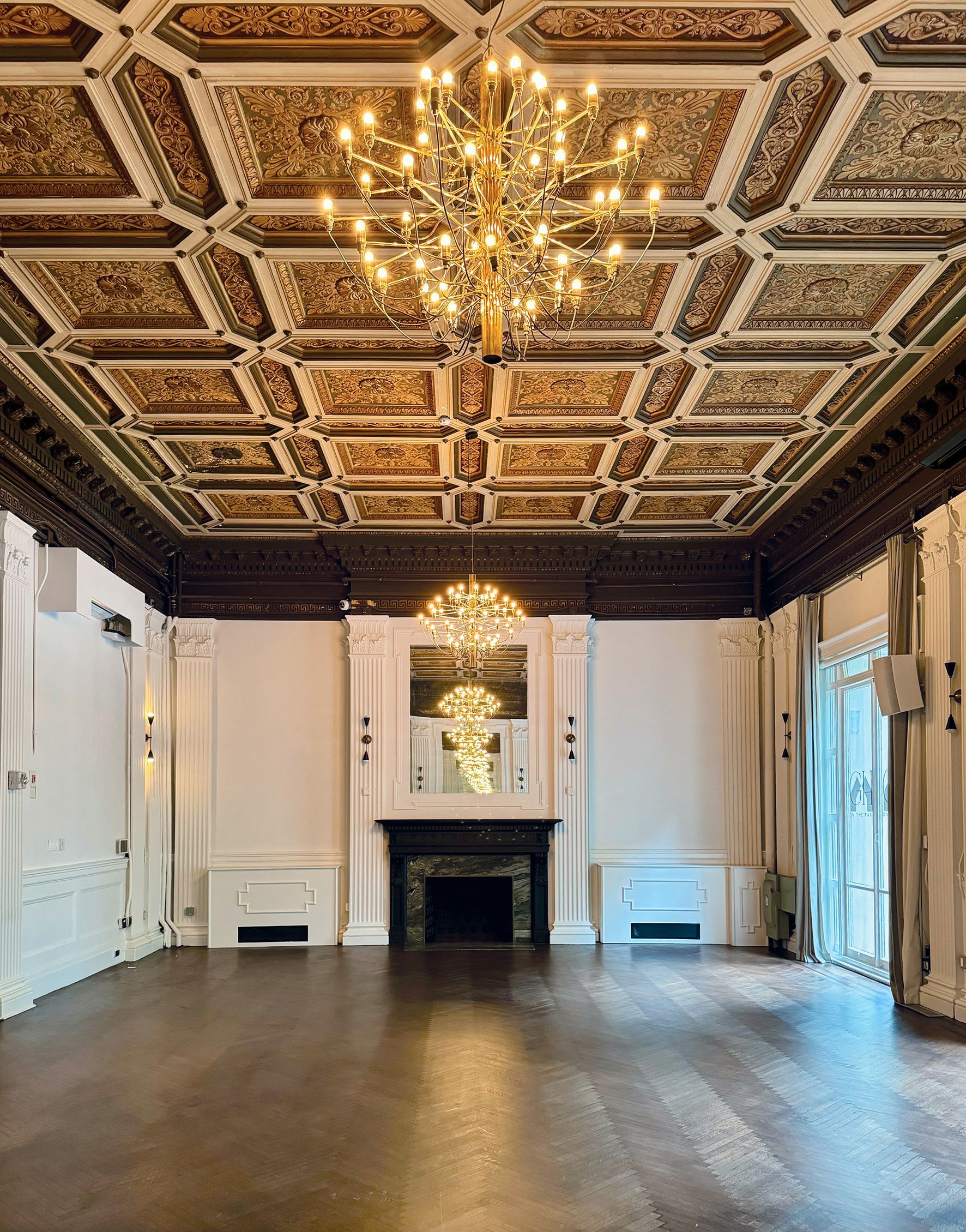 An empty room with a fireplace and a chandelier hanging from the ceiling.