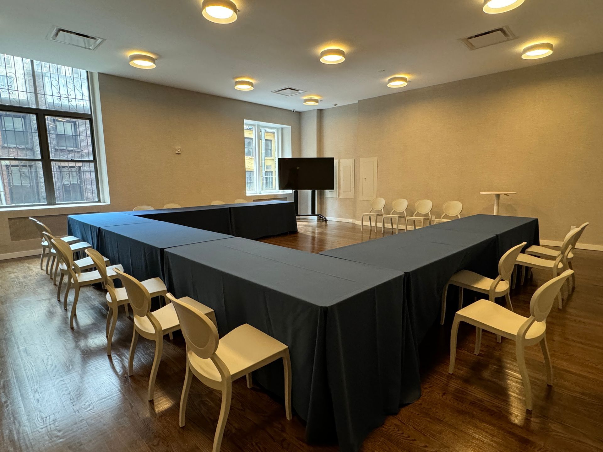 A conference room with tables and chairs and a flat screen tv.