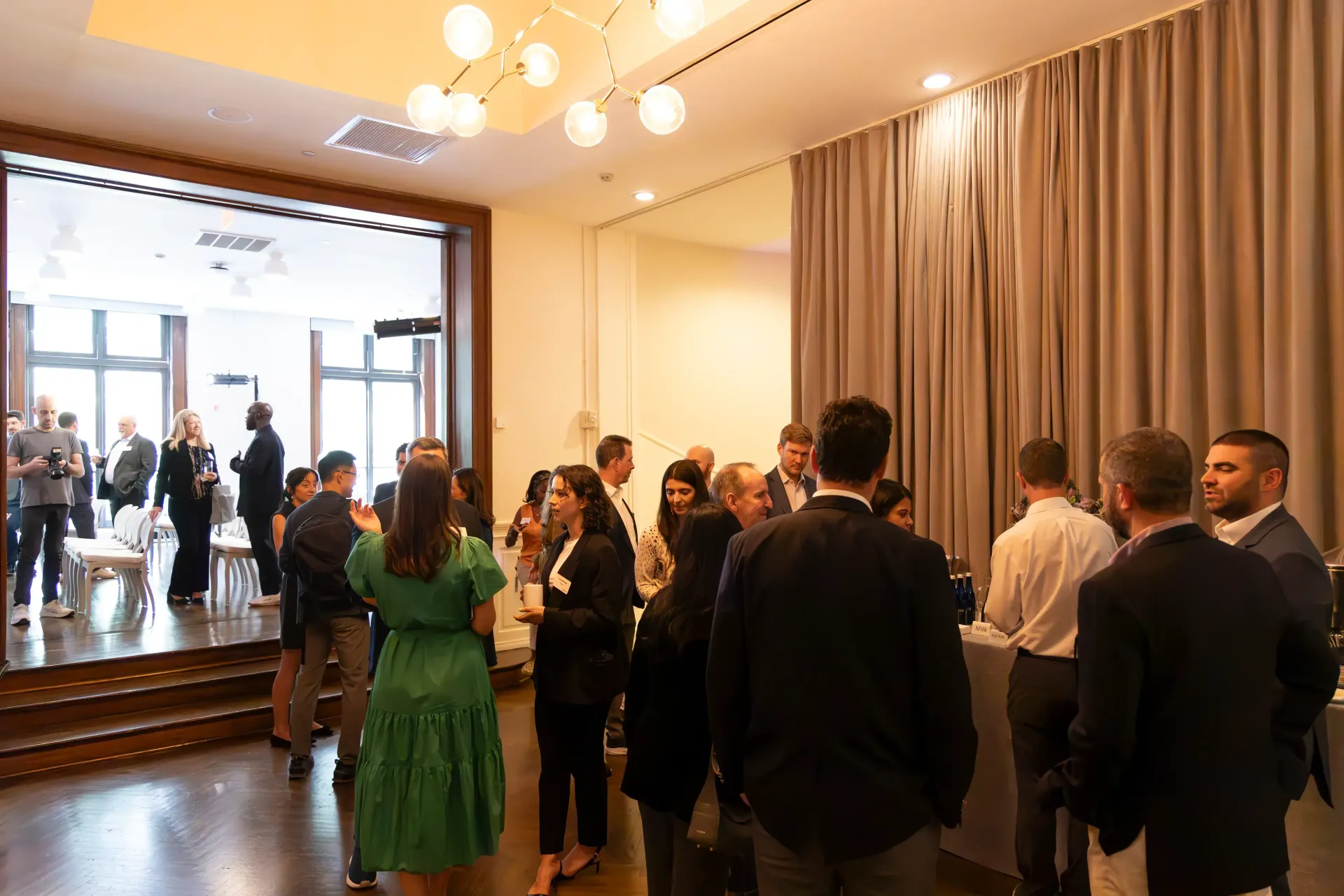 People at an event, indoors, gathered near doorway, some looking outside.