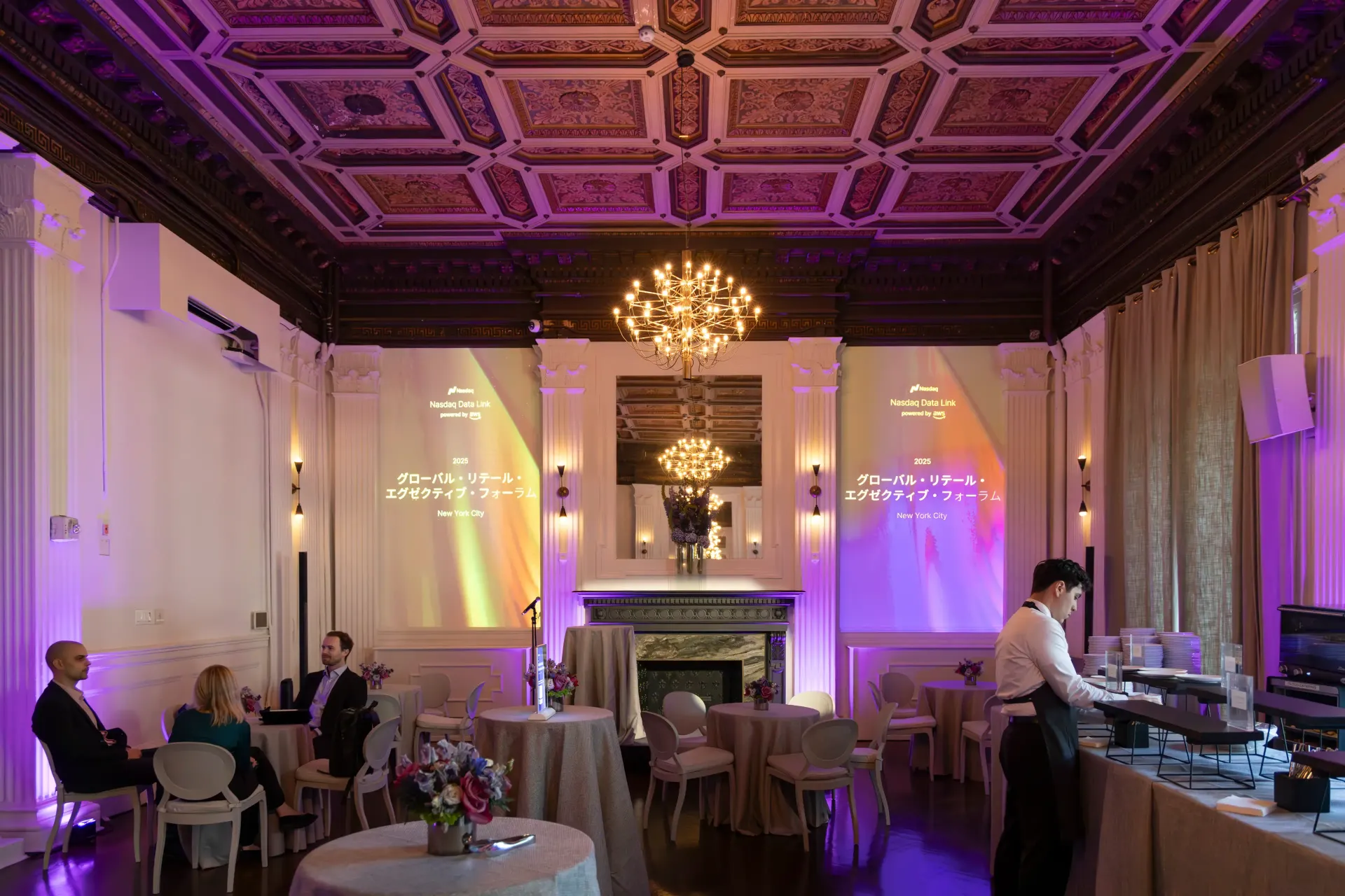 Elegant event space with guests, tables, a server, and decorative ceiling.
