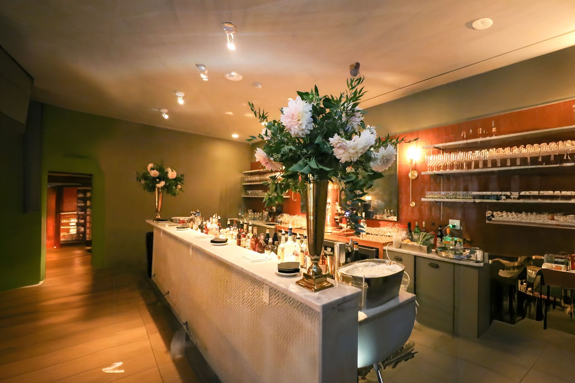 A long counter in a restaurant with a vase of flowers on it.