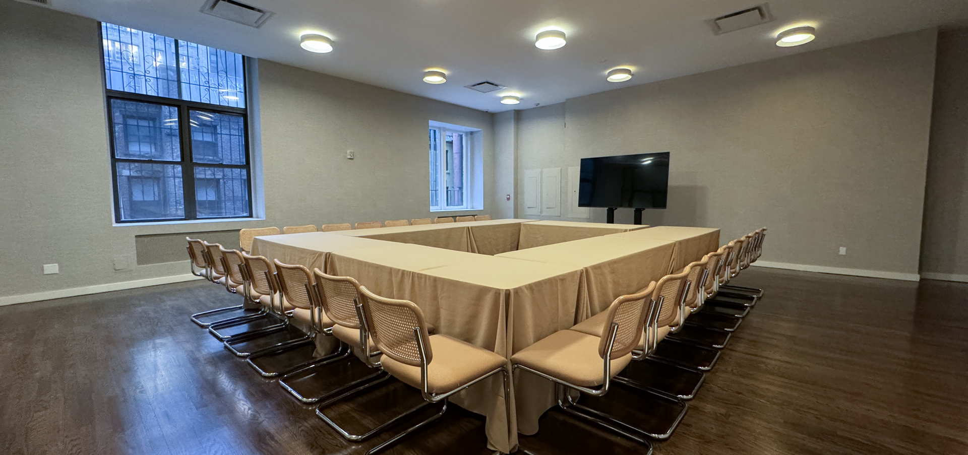 a conference room with a long table and chairs and a flat screen tv .