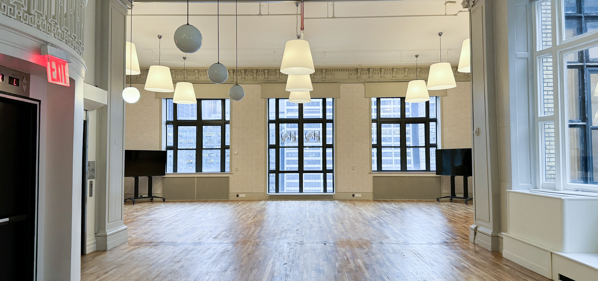 a large empty room with lots of windows and lamps hanging from the ceiling .