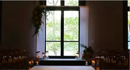 A wedding ceremony is taking place in a dark room with candles and flowers.