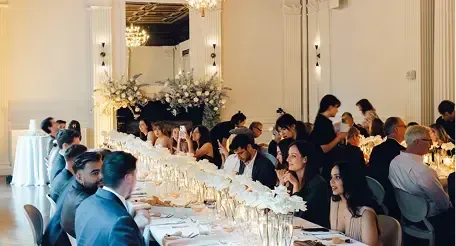 A group of people are sitting at long tables at a wedding reception.