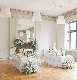 There is a long table with flowers on it in the middle of the room.