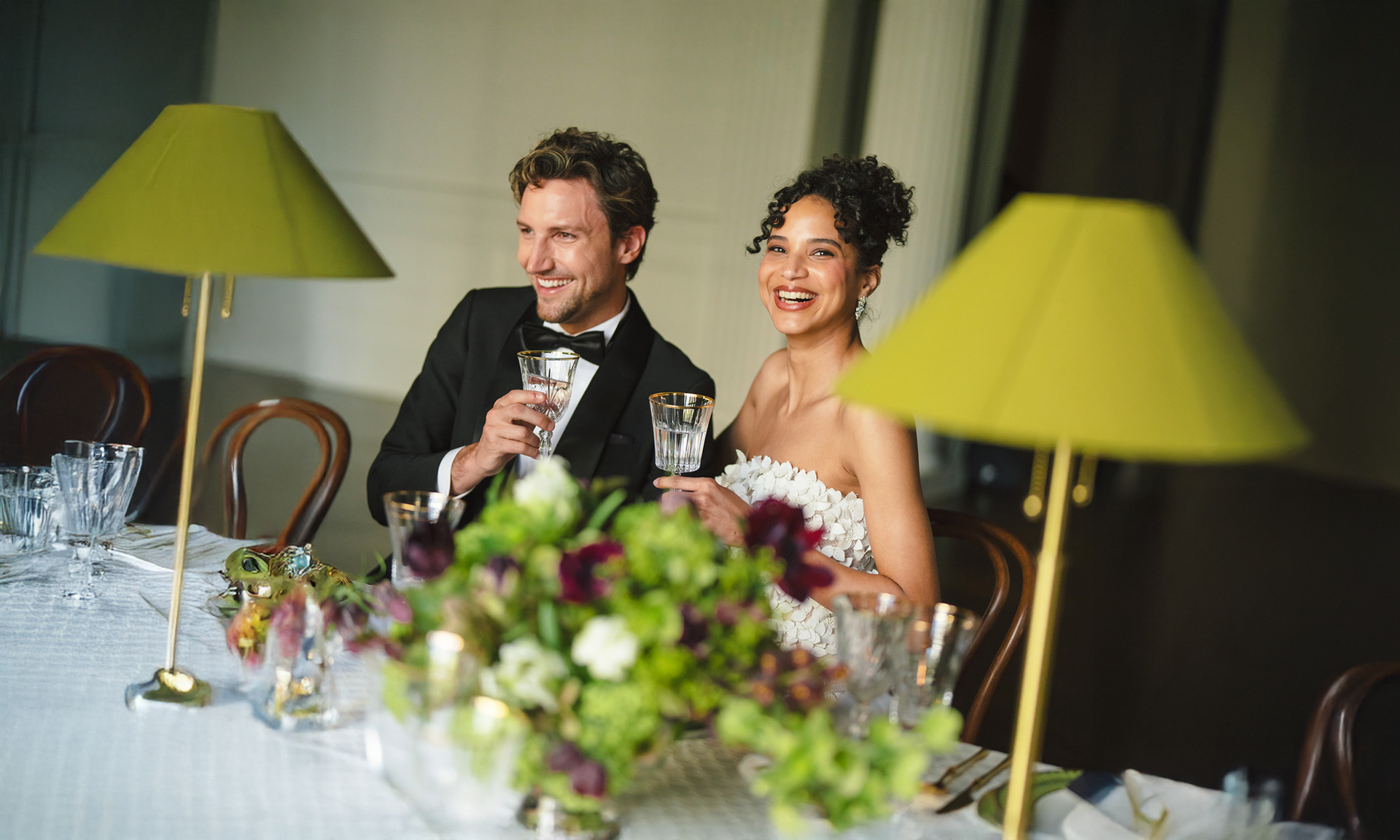 A snowy winter scene with an ice rink, small wooden stalls, and trees strung with lights.