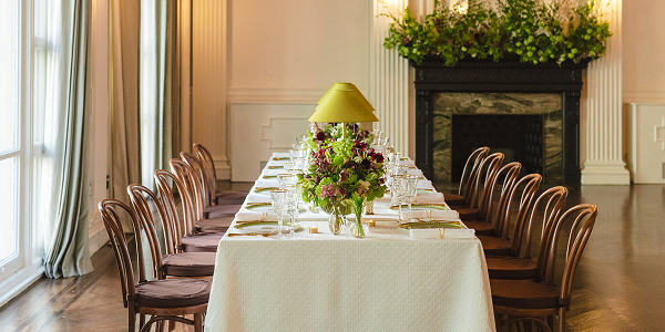 Four people in formal wear toast with champagne in front of a decorated Christmas tree.