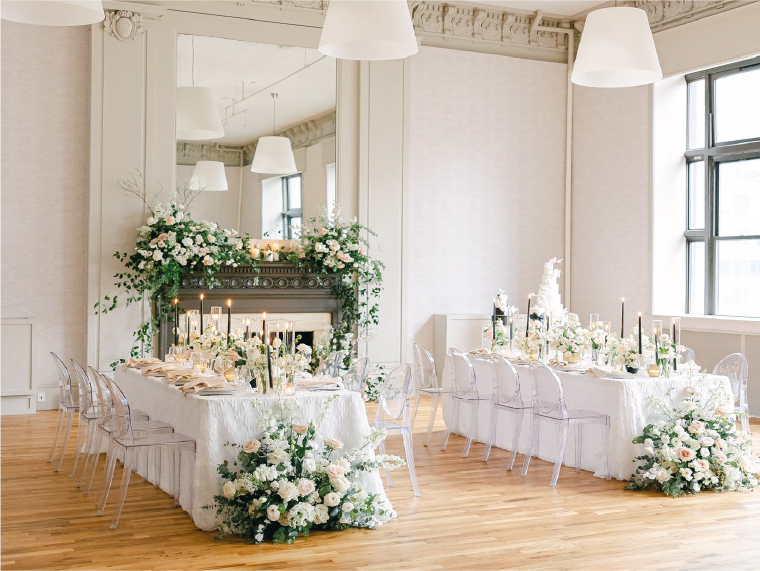 Couple in formal attire, smiling on a carousel, festive Christmas lights in the background.