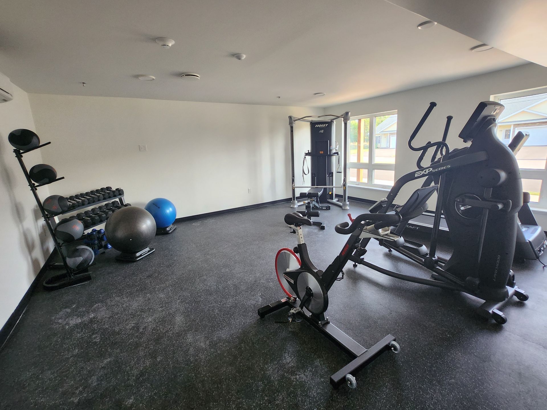 Professional gym equipment in the fitness centre with bright windows, cardio machines, exercise balls and free weights. At The Simmons in Summerside, PEI.