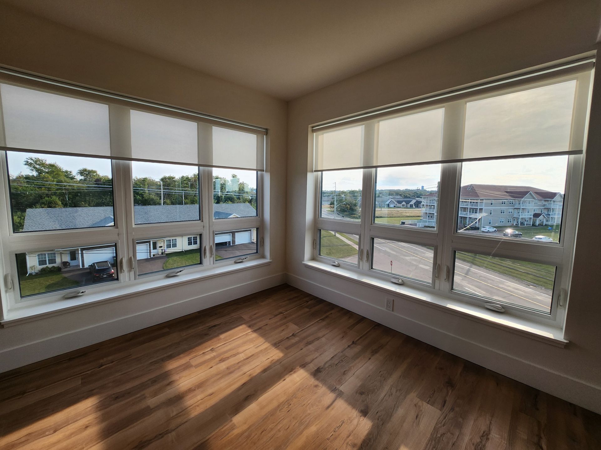 Two large bright 3-panel windows in the living room with hardwood floors at The Simmons apartment building.
