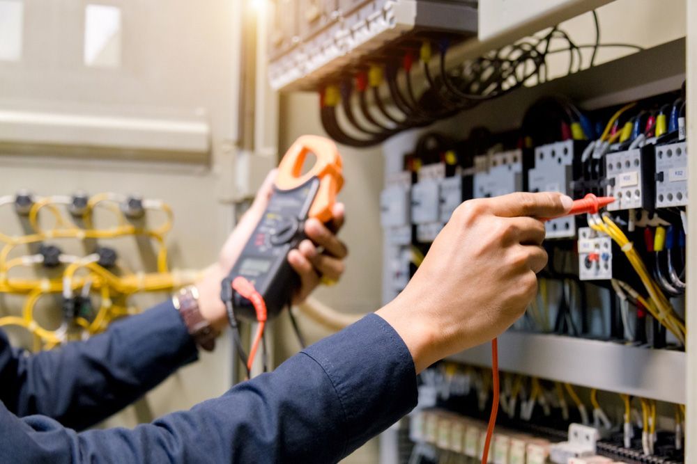 A Man Is Working On An Electrical Panel With A Multimeter — Coppo's Electrical In Helensvale, QLD
