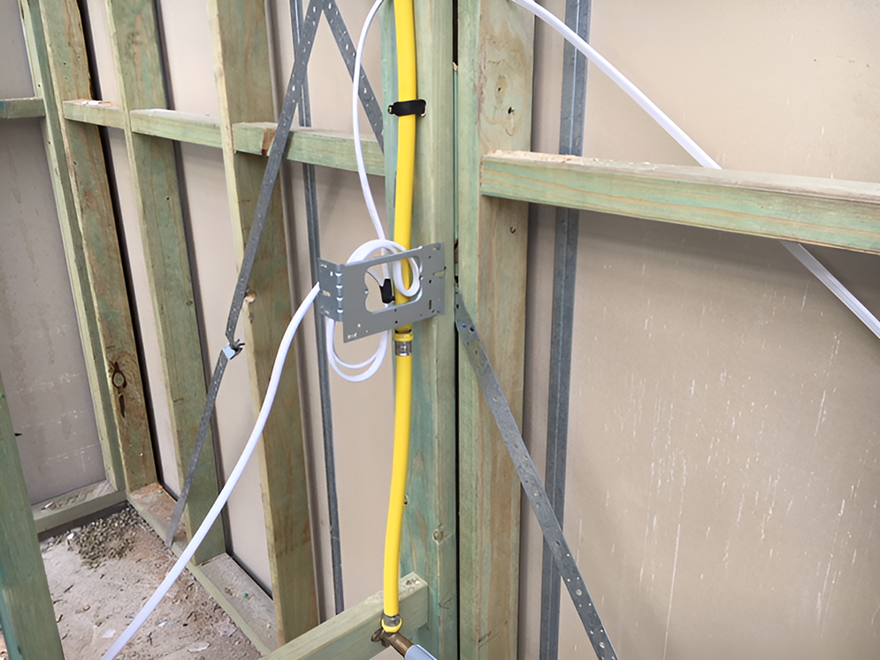 A Yellow Pipe is Attached to a Wooden Wall — Coppo's Electrical in Pimpama, QLD