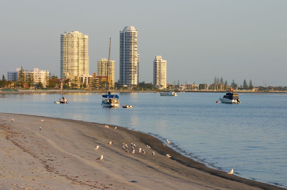 A Beach With Boats in the Water and Buildings in the Background — Coppo's Electrical in Runaway Bay, QLD