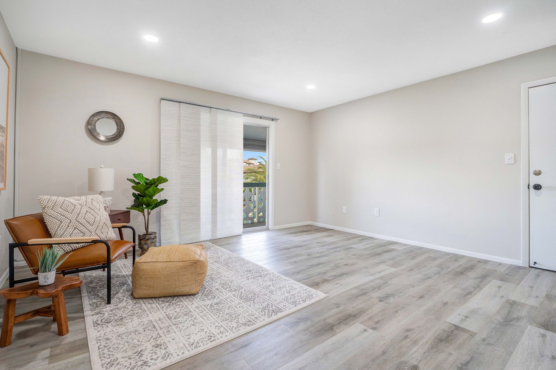 A living room with hardwood floors , a chair and a rug.
