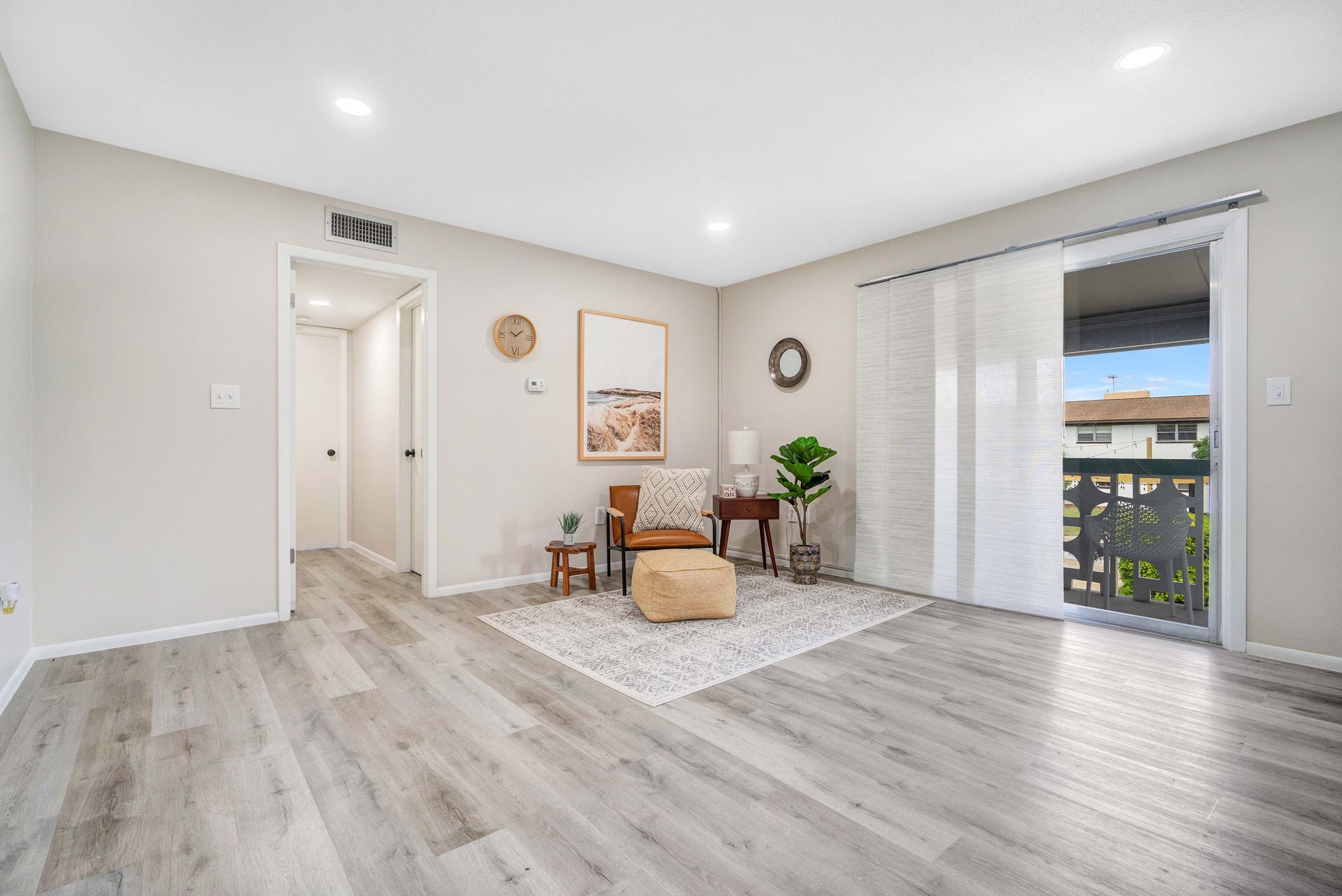 A living room with hardwood floors and a sliding glass door leading to a balcony.