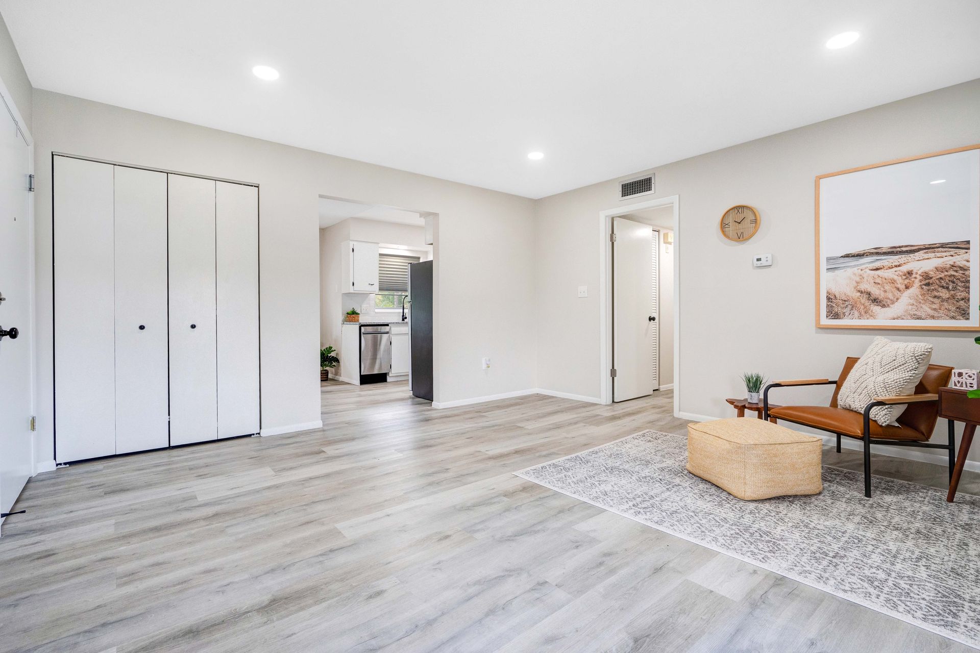 A living room with hardwood floors , a chair , and a picture on the wall.