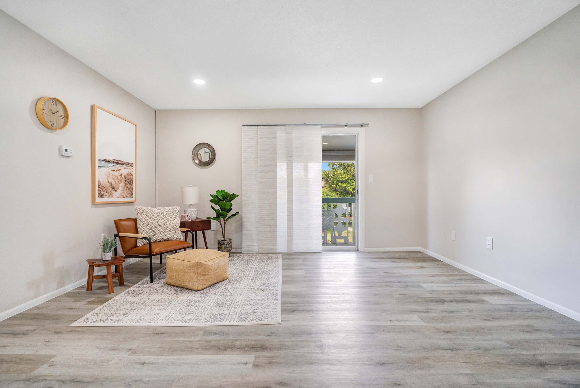 A living room with hardwood floors , a chair and a rug.