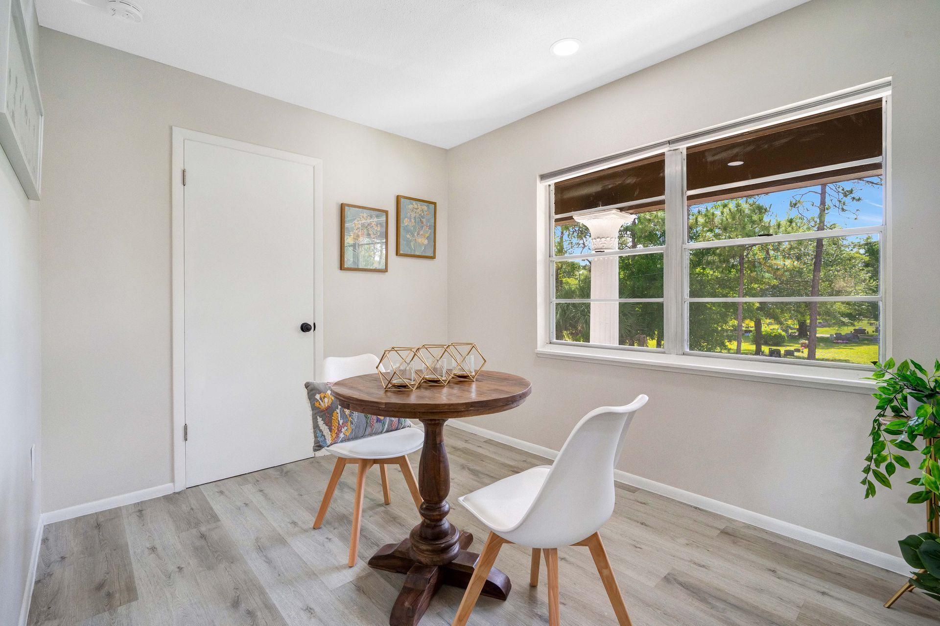 A room with a table and chairs in front of a window.