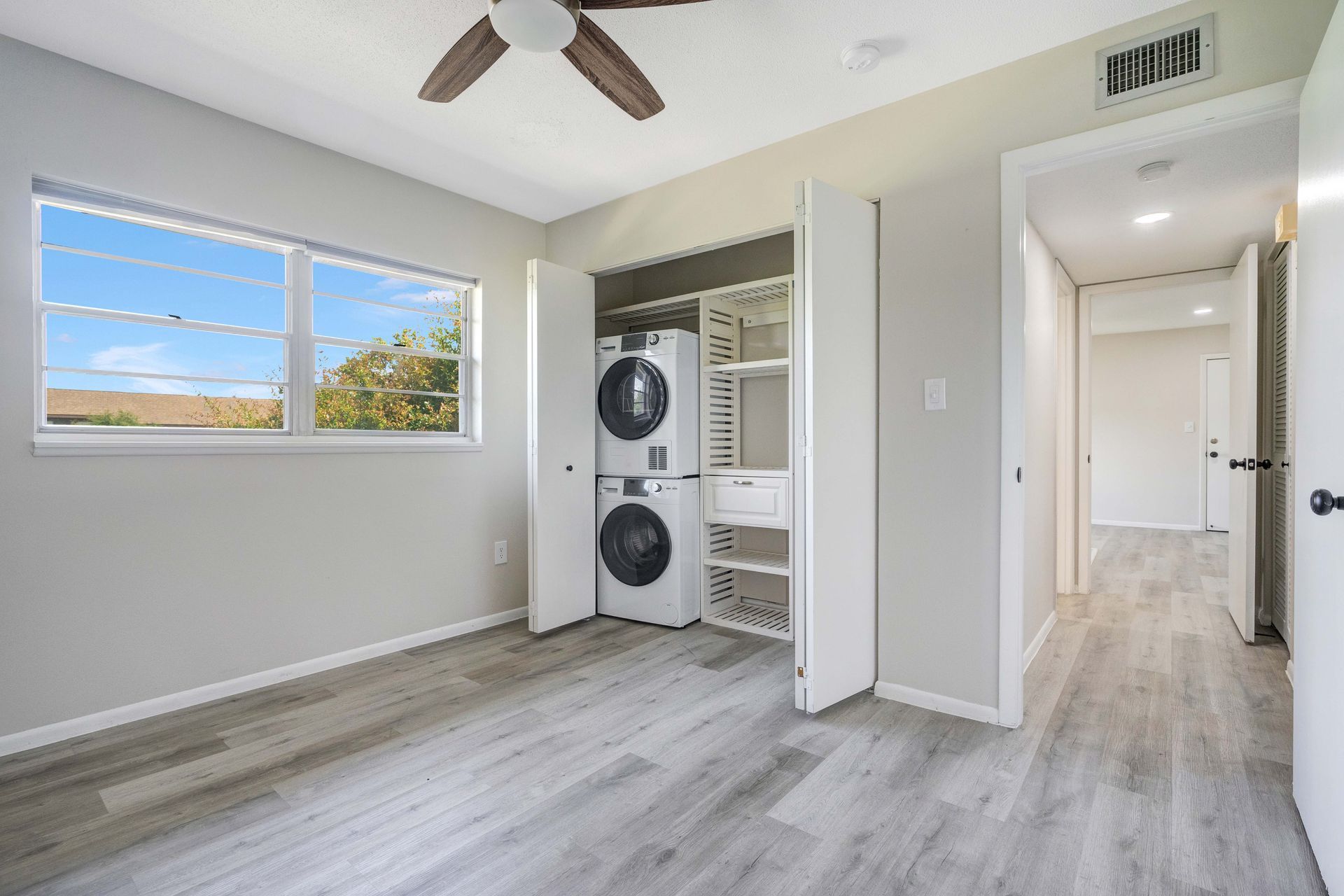 A bedroom with a washer and dryer in it and a ceiling fan.