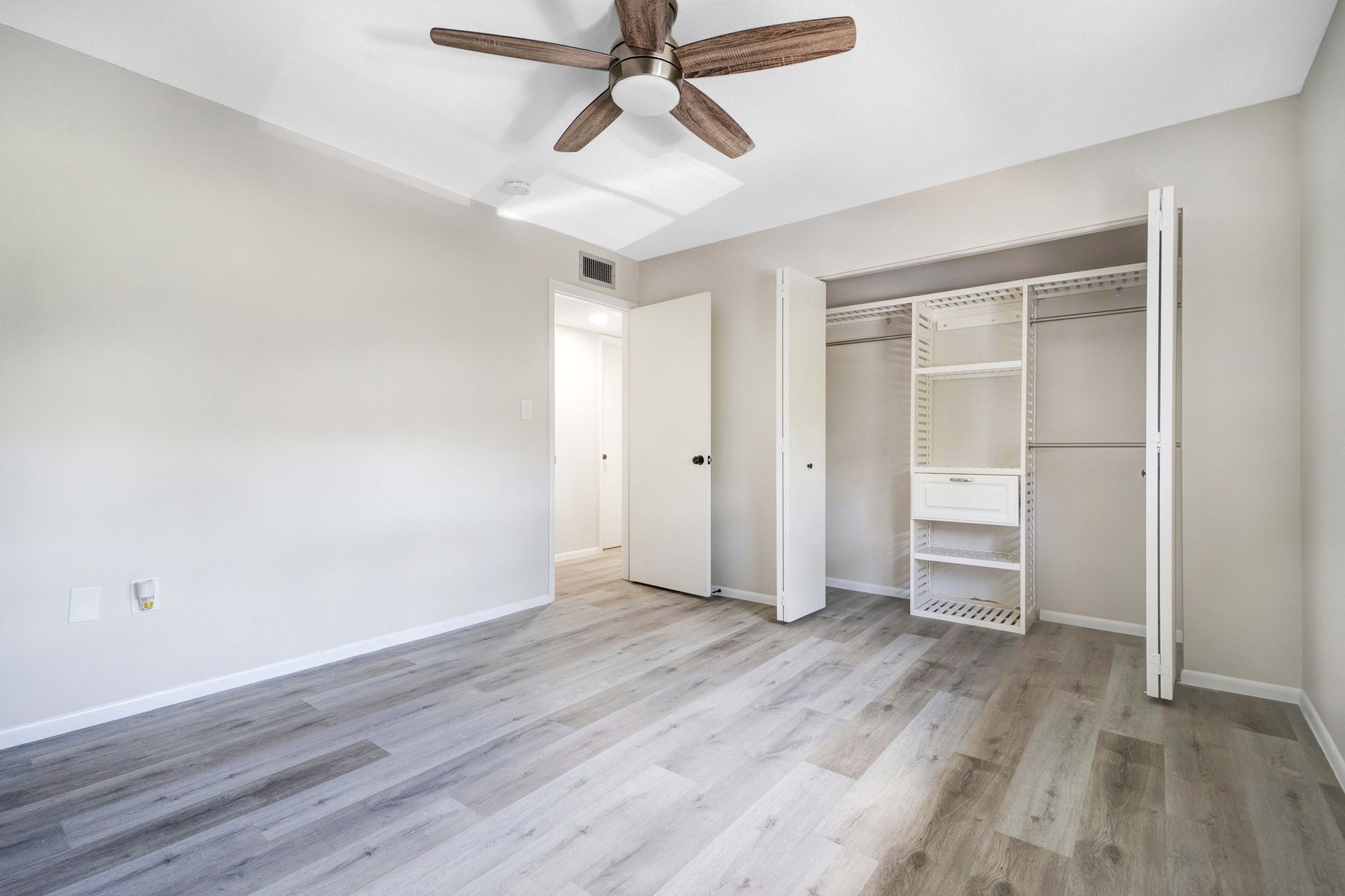 An empty bedroom with hardwood floors and a ceiling fan.