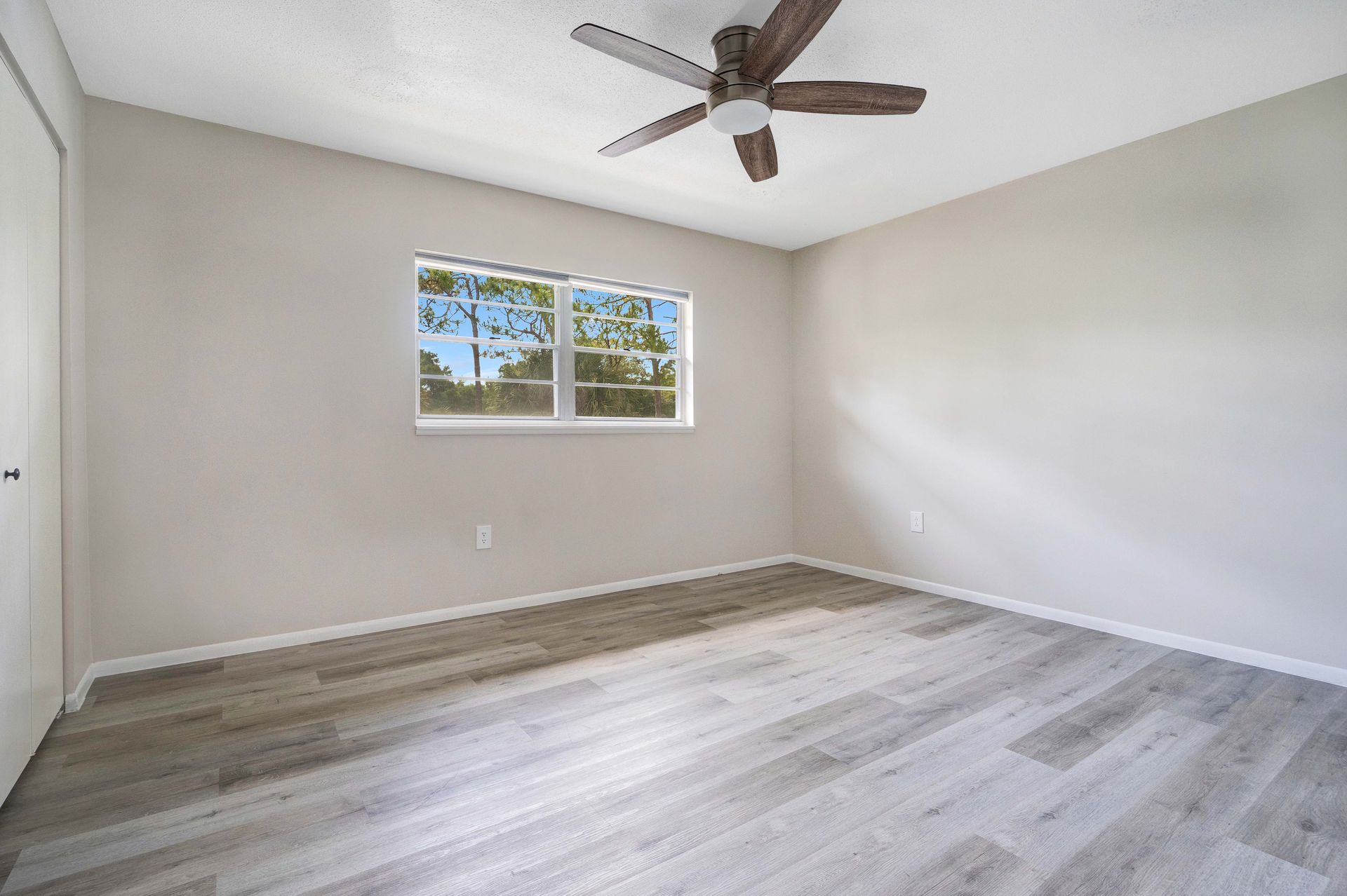 An empty bedroom with hardwood floors and a ceiling fan.