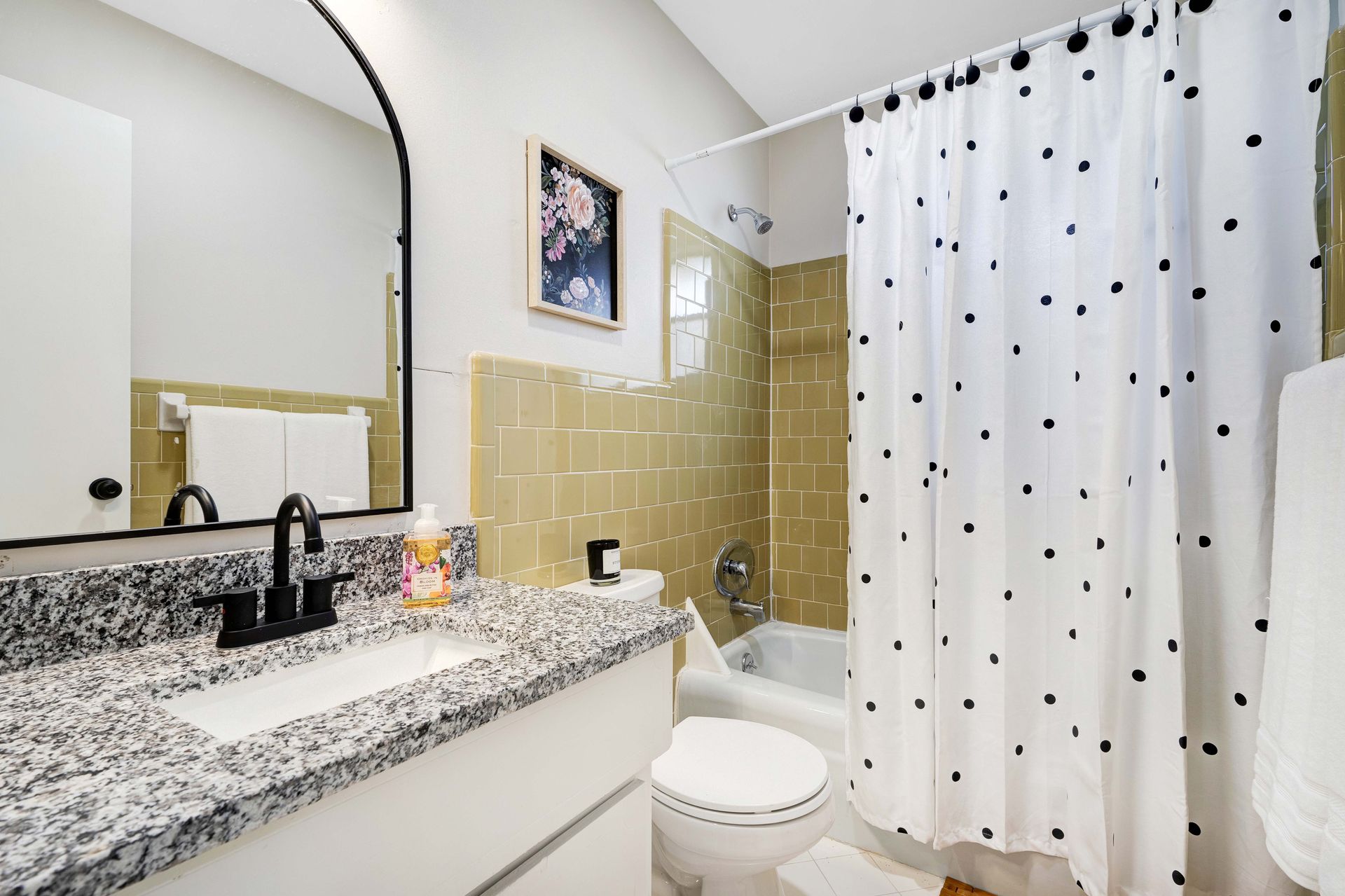 A bathroom with a sink , toilet , shower curtain and mirror.