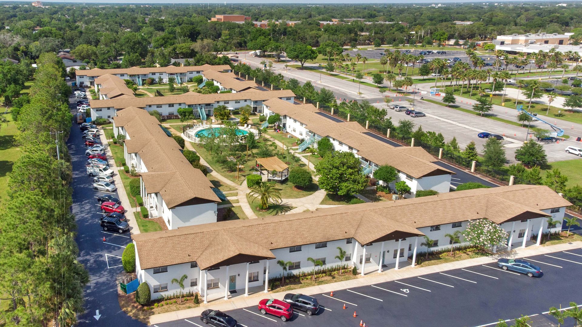 An aerial view of a large apartment complex with cars parked in front of it.