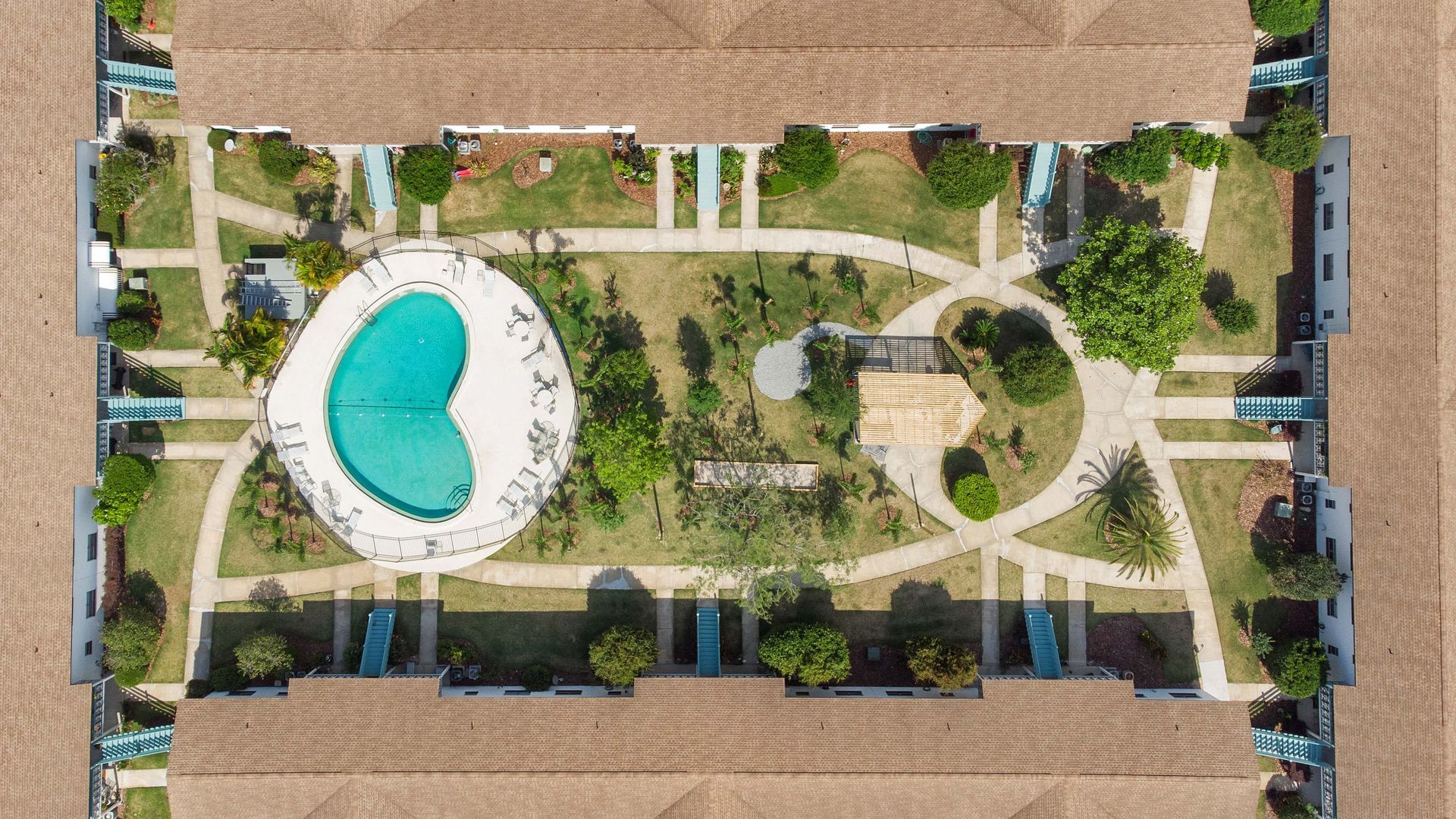 An aerial view of a building with a pool in the middle of it.