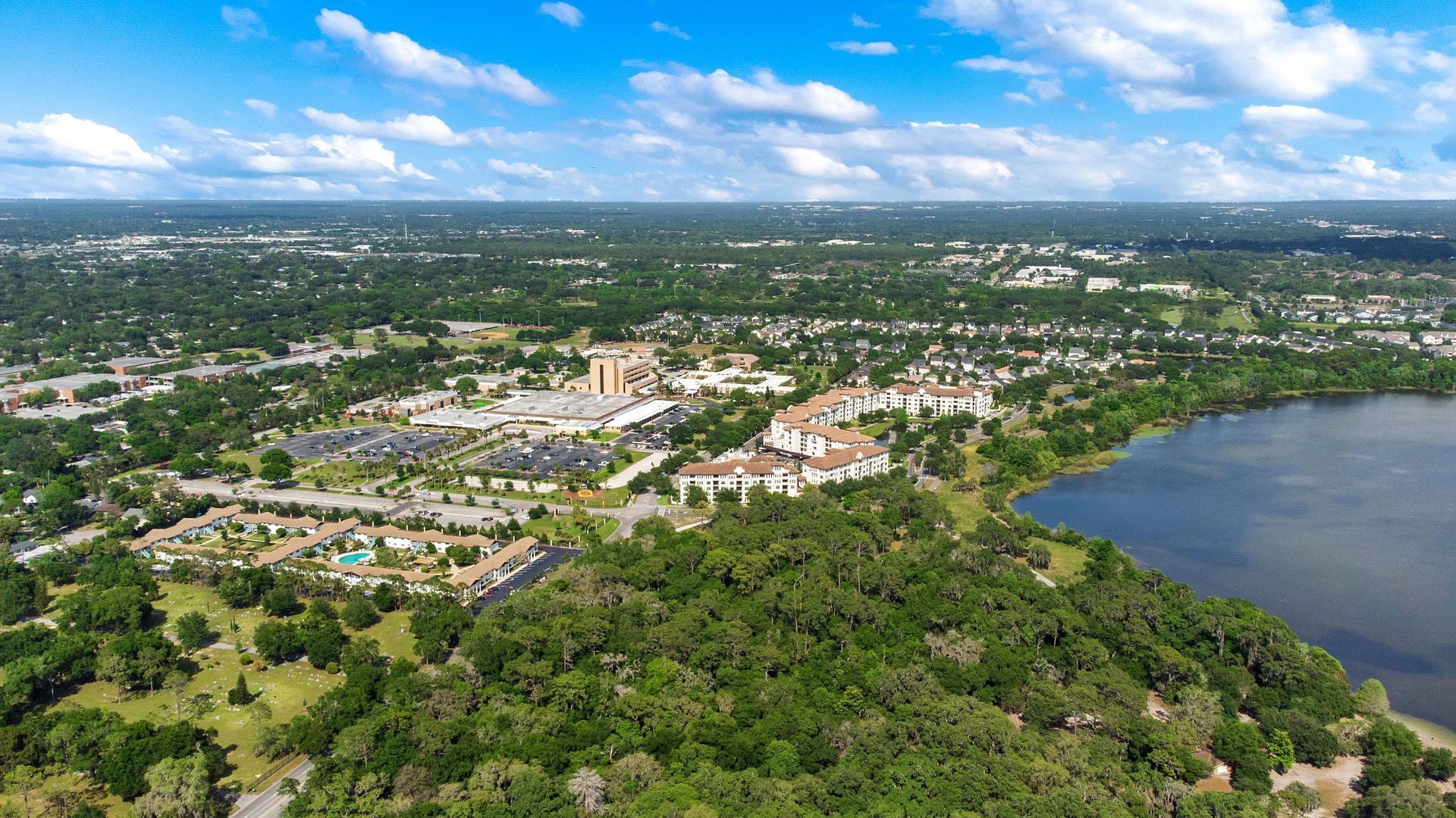 An aerial view of a city surrounded by trees and a lake.