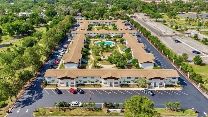 An aerial view of a large apartment complex surrounded by trees and a parking lot.