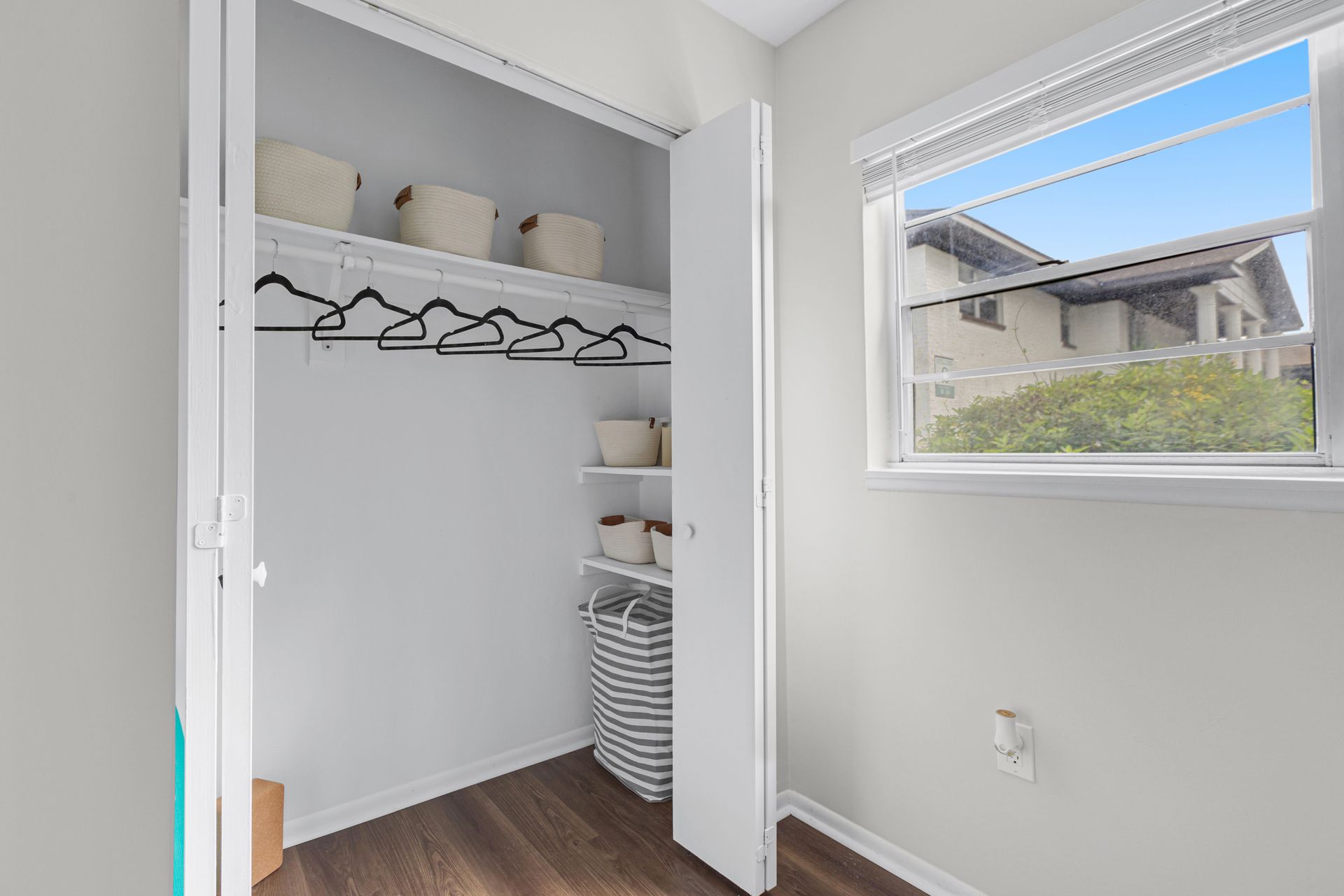 A walk in closet with a window and a laundry basket.
