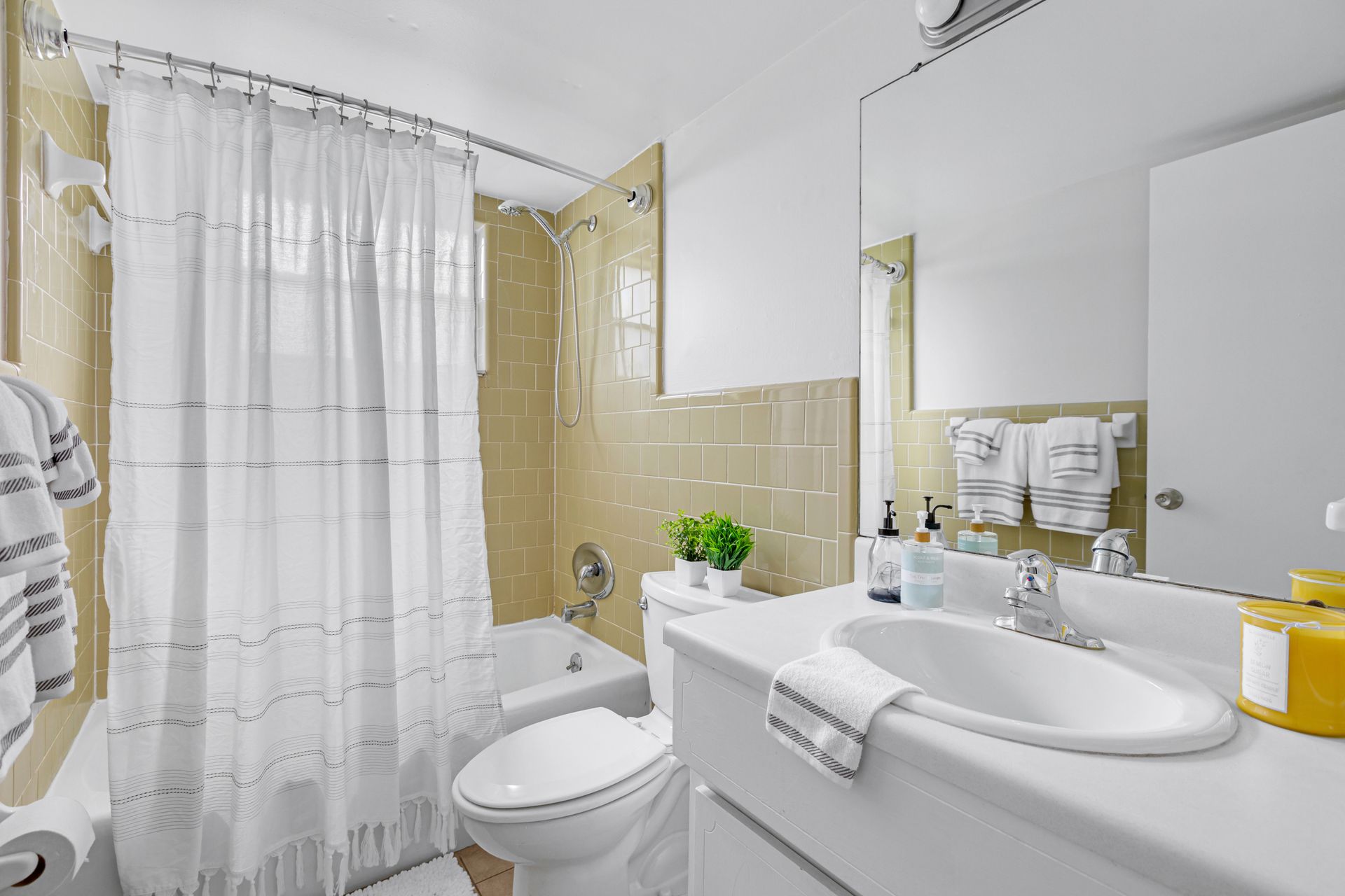A bathroom with a toilet , sink , tub and shower curtain.