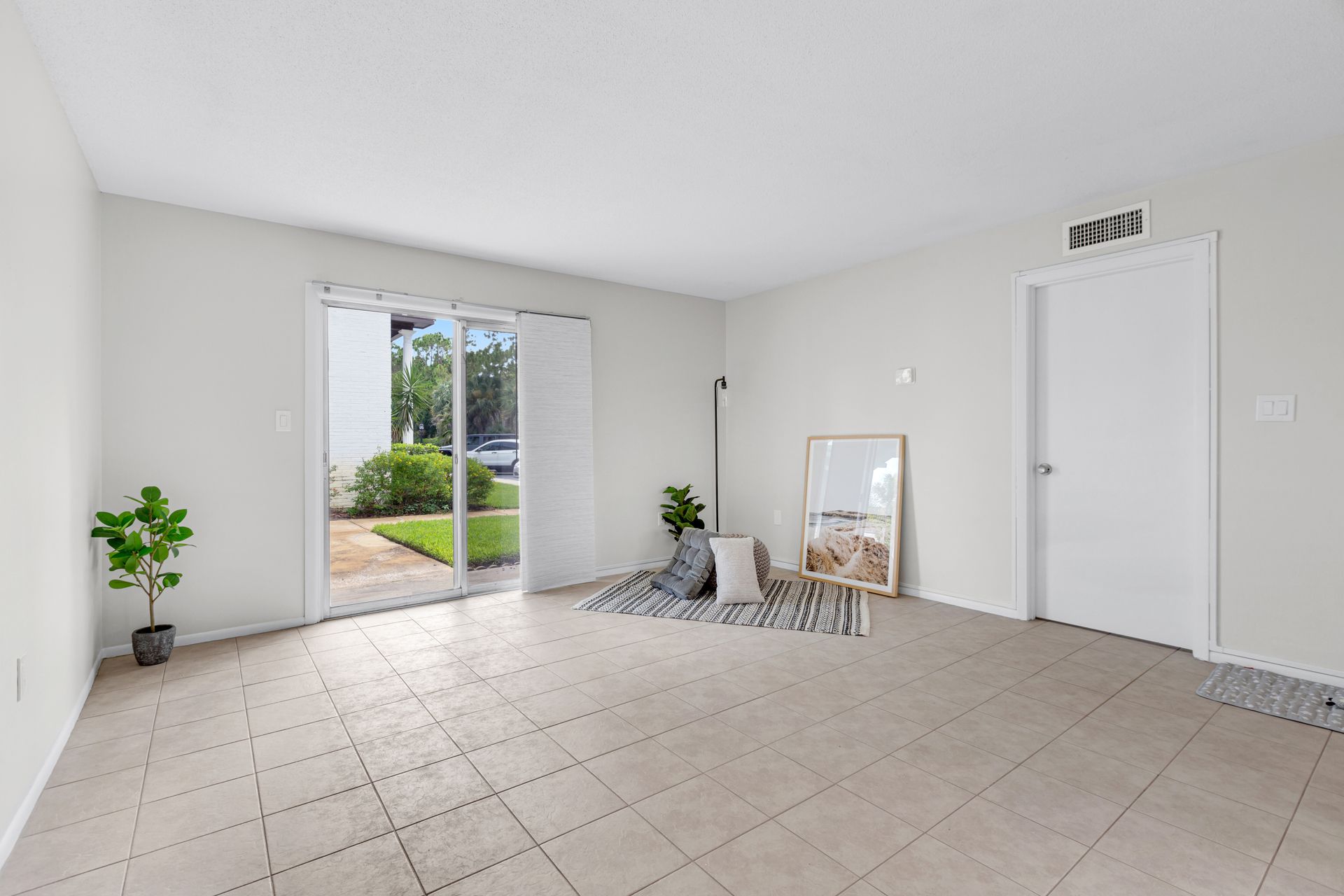 An empty living room with a sliding glass door leading to a patio.